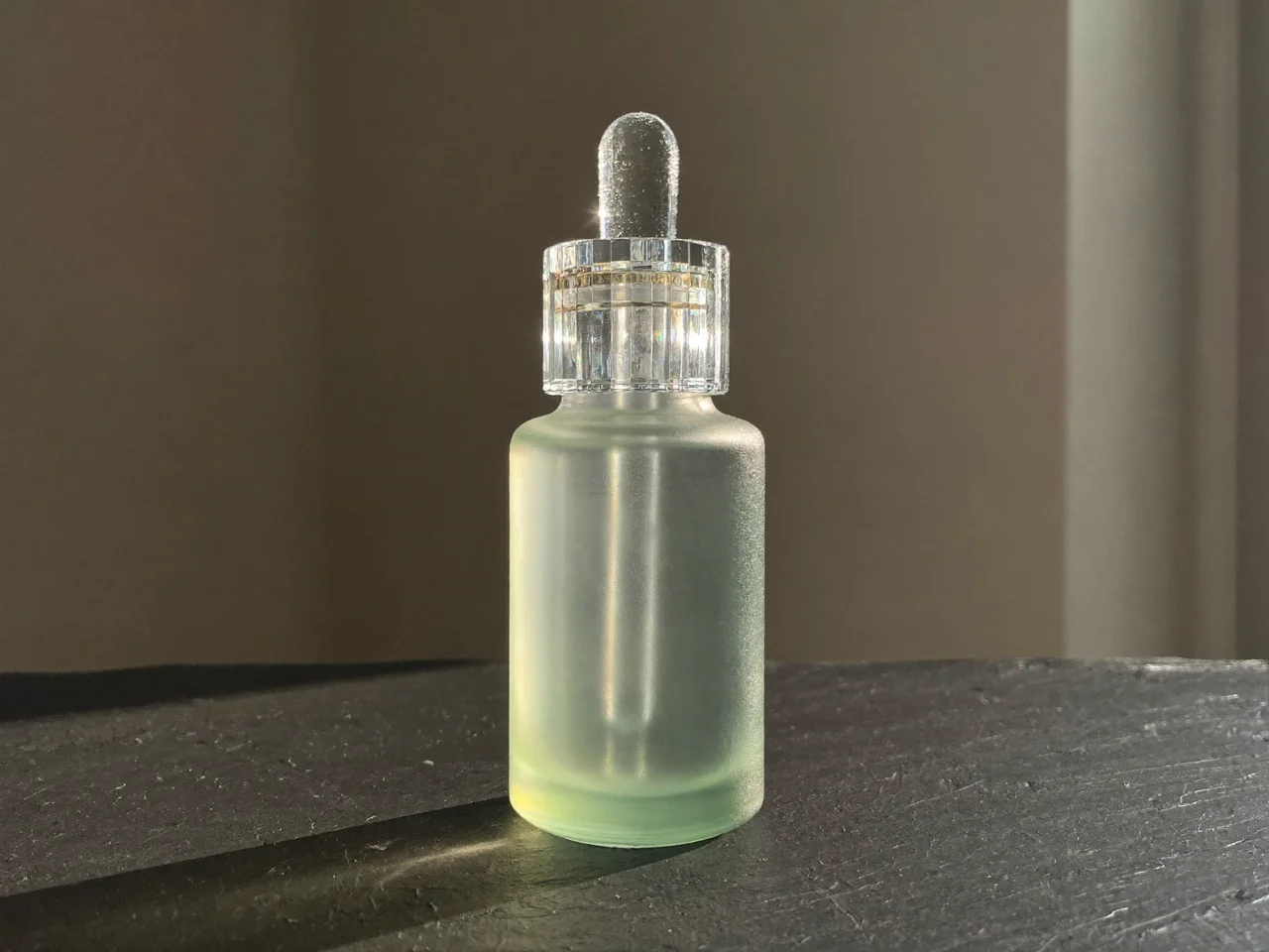 Flacon de sérum givré à pipette sur ardoise, goutte sur le verre