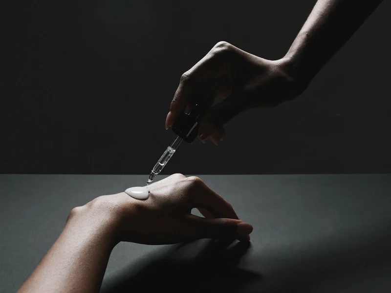 Main appliquant un sérum à la pipette sur le dos de l'autre main